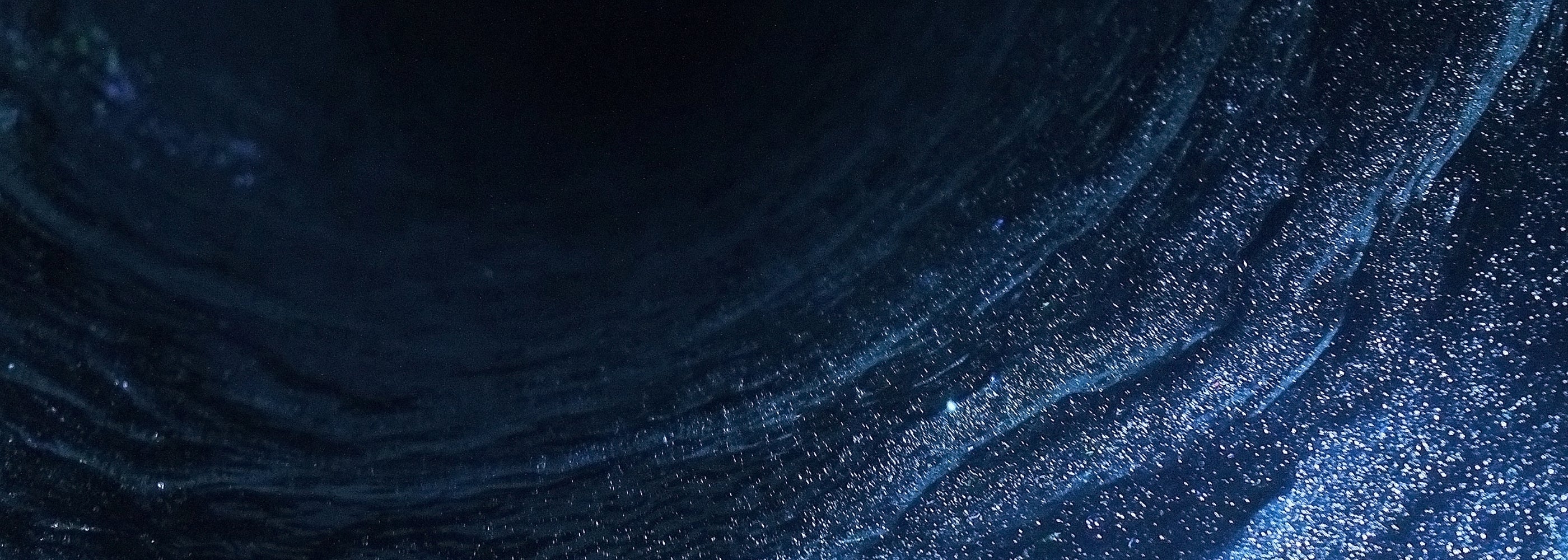 Abstract dark blue water with shimmering speckles of hash